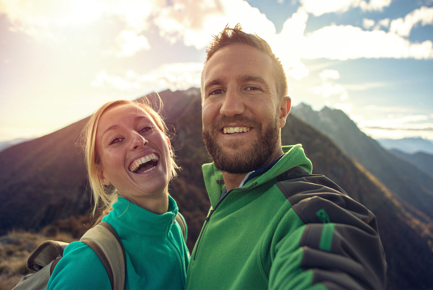 Paar im Freien macht ein Selbstporträt mit Blick auf Berge im Hintergrund