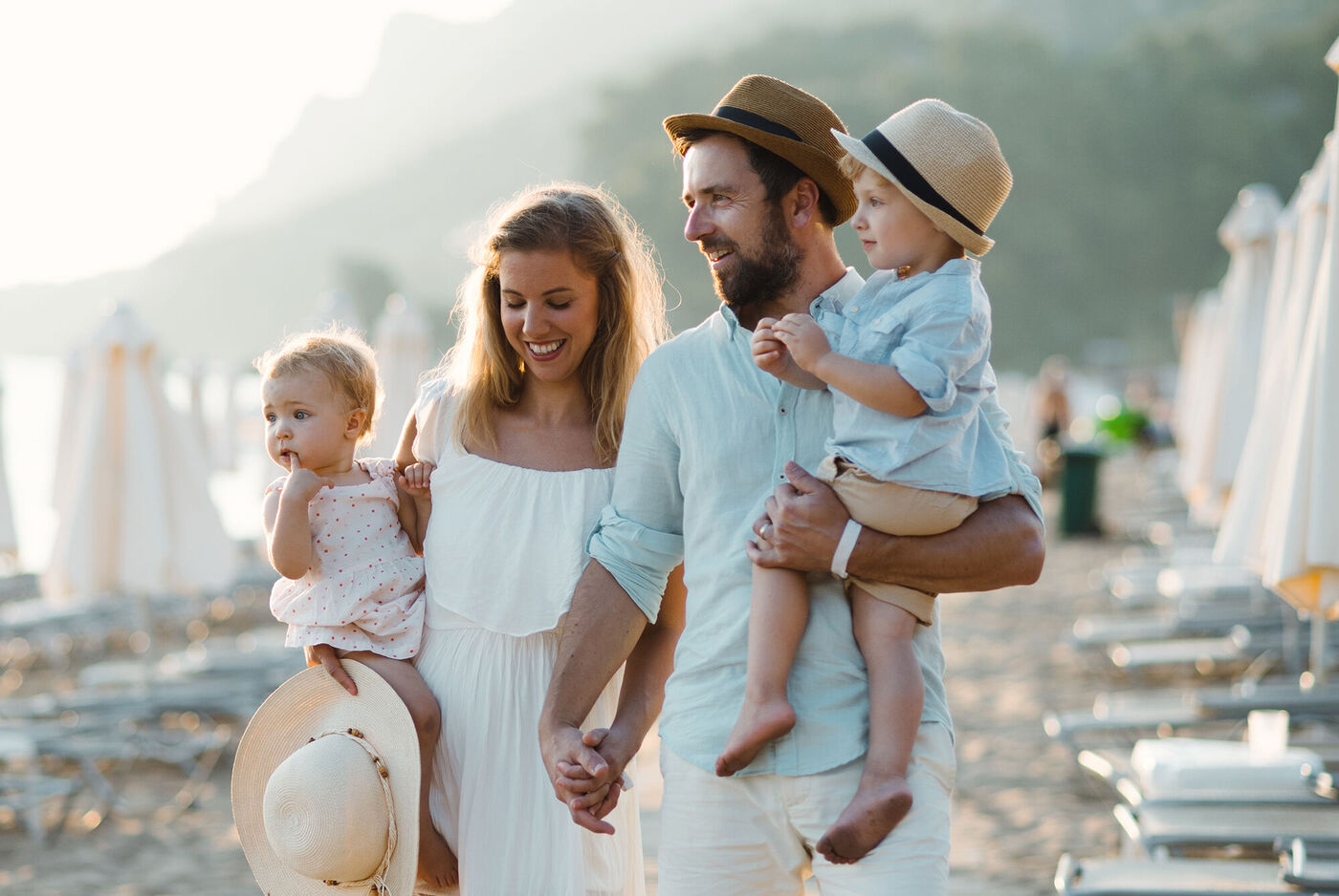 Eine glückliche Familie am Strand mit zwei kleinen Kindern. Sie lachen und genießen den sonnigen Tag.