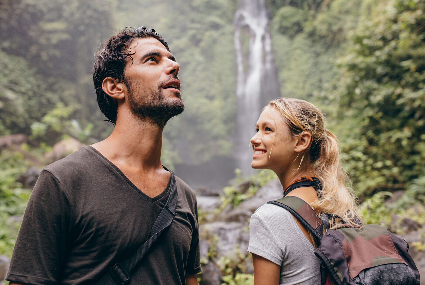 Paar steht am Wasserfall in der Natur und genießt den Moment