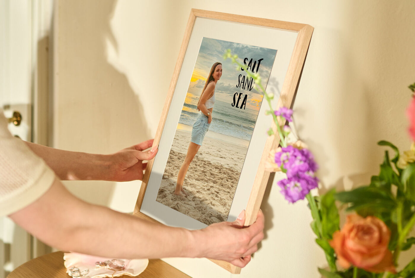 Eine Person hält einen Bilderrahmen mit einem Strandfoto.